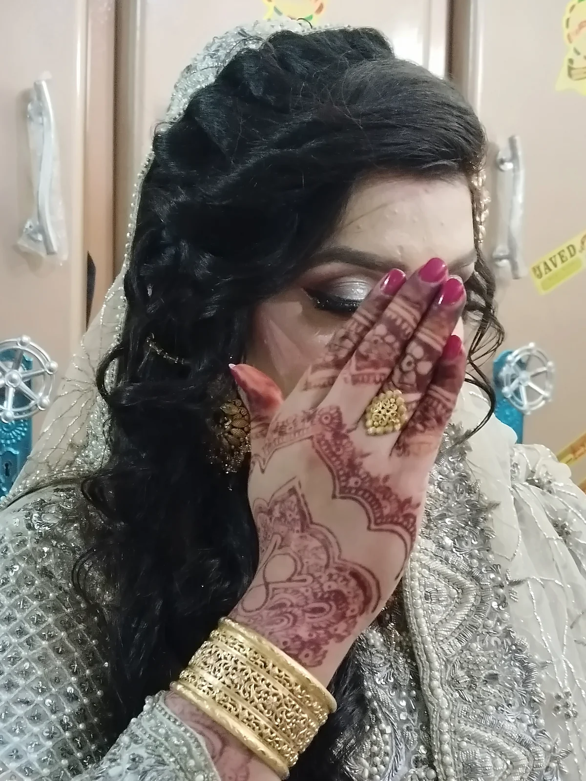 Bride holding up her mehndi-decorated hand at Glow Beauty Salon Kasur
