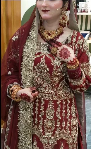 Bride in maroon dress with gold jewellery — bridal makeup by Glow Beauty Salon Kasur